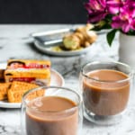 Ginger Tea in 2 glass cups with cookies and ginger in the background