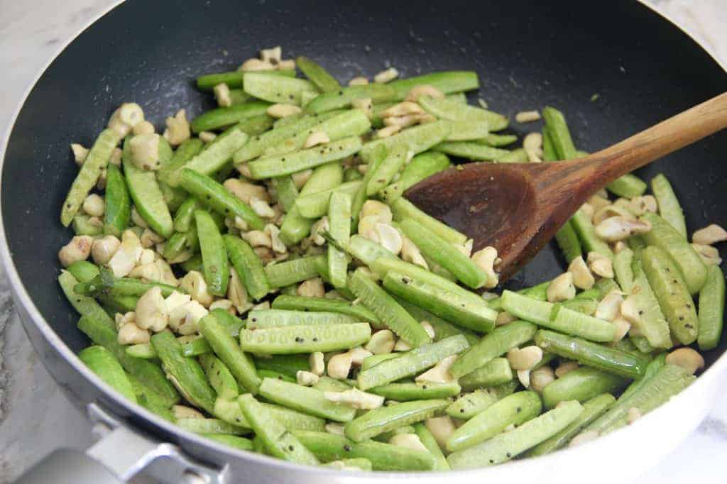 cooking tindora and cashews in a pan 