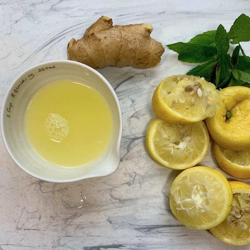 lemon juice, ginger, mint and lemon peels on cutting board