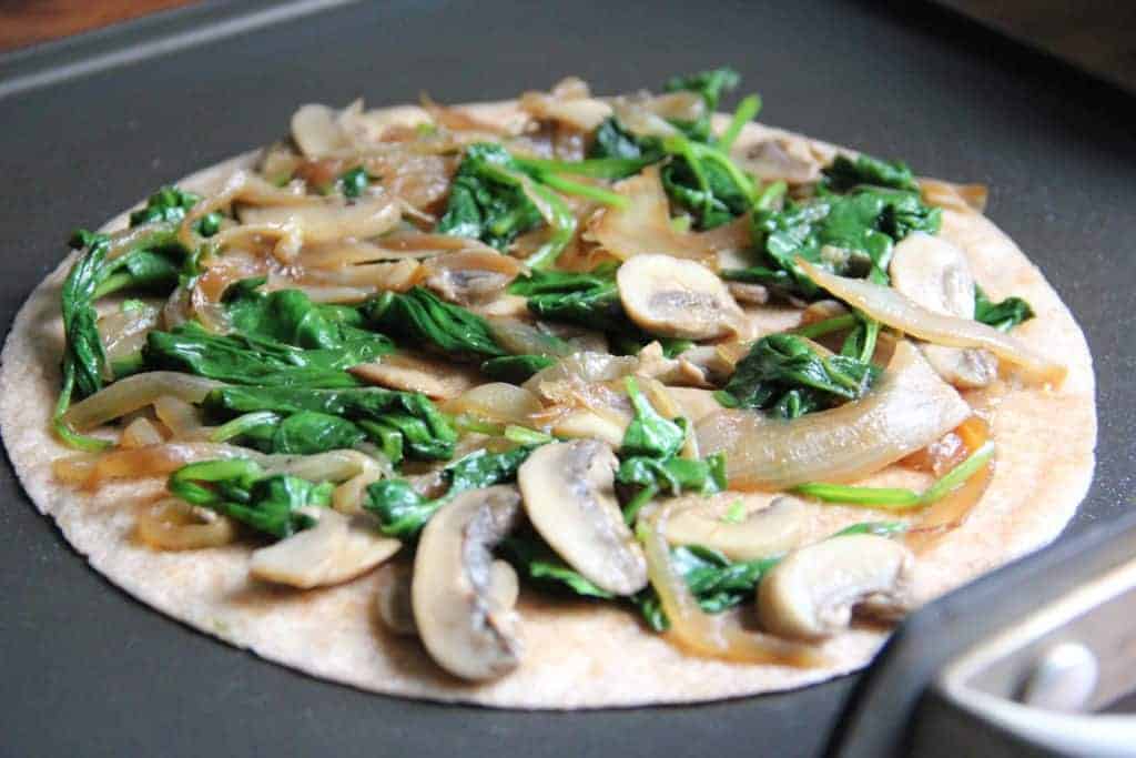 tortilla topped with spinach, onion and mushroom filling 