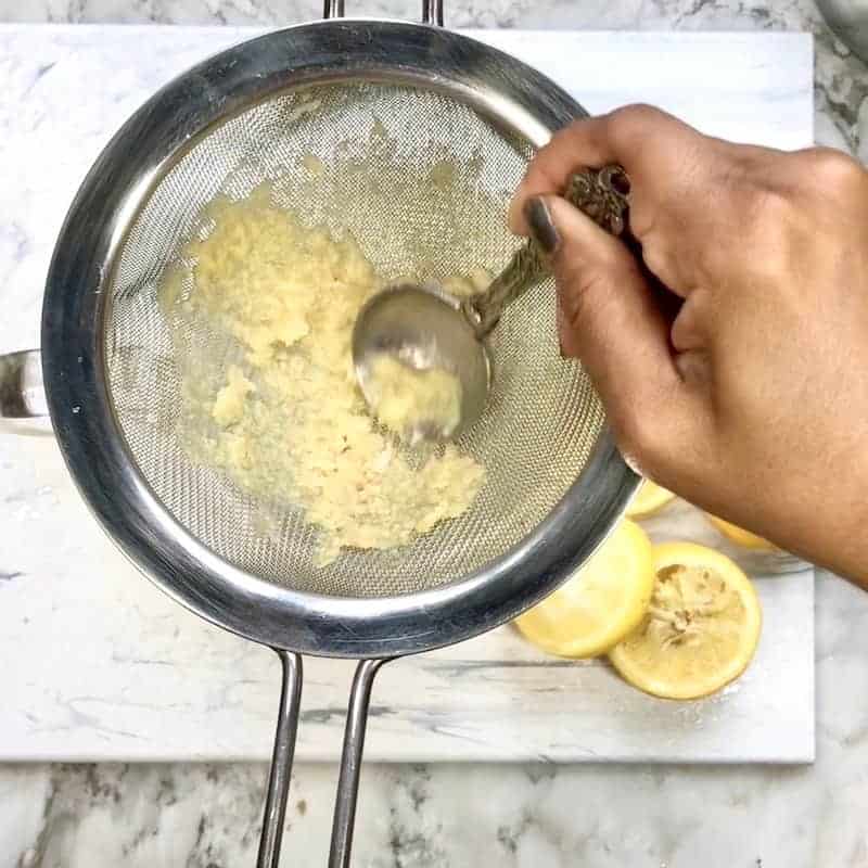pouring ginger concentrate through strainer