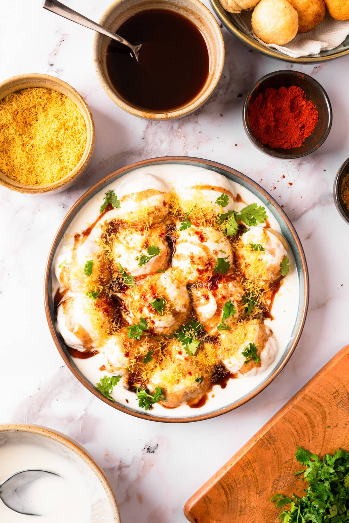 Dahi Vada in a bowl with extra toppings on the side