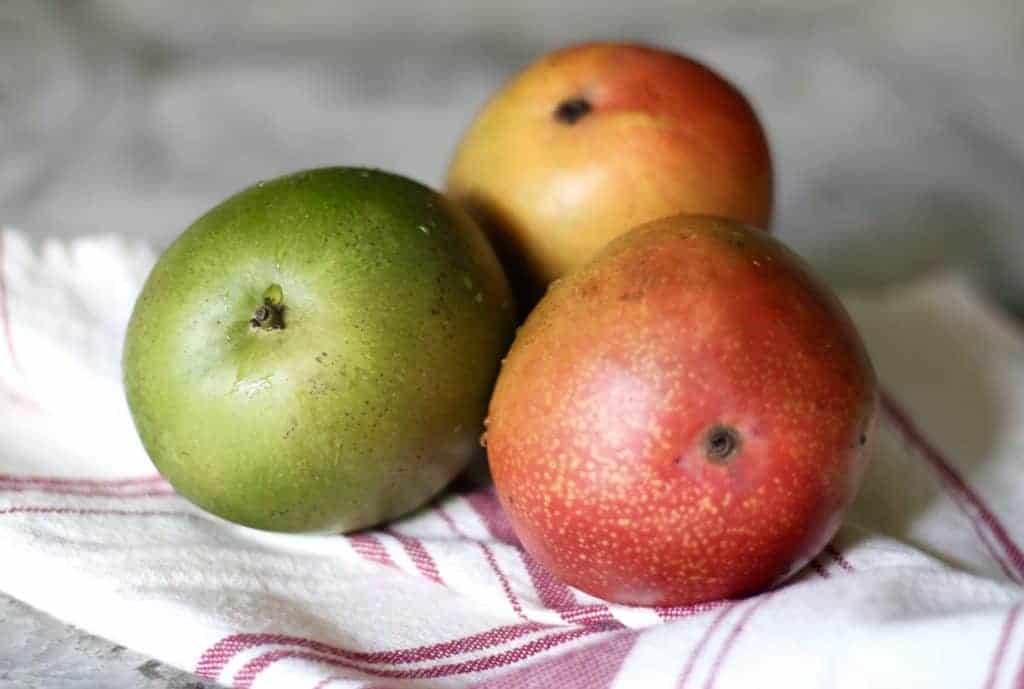 three mangoes on dish towel
