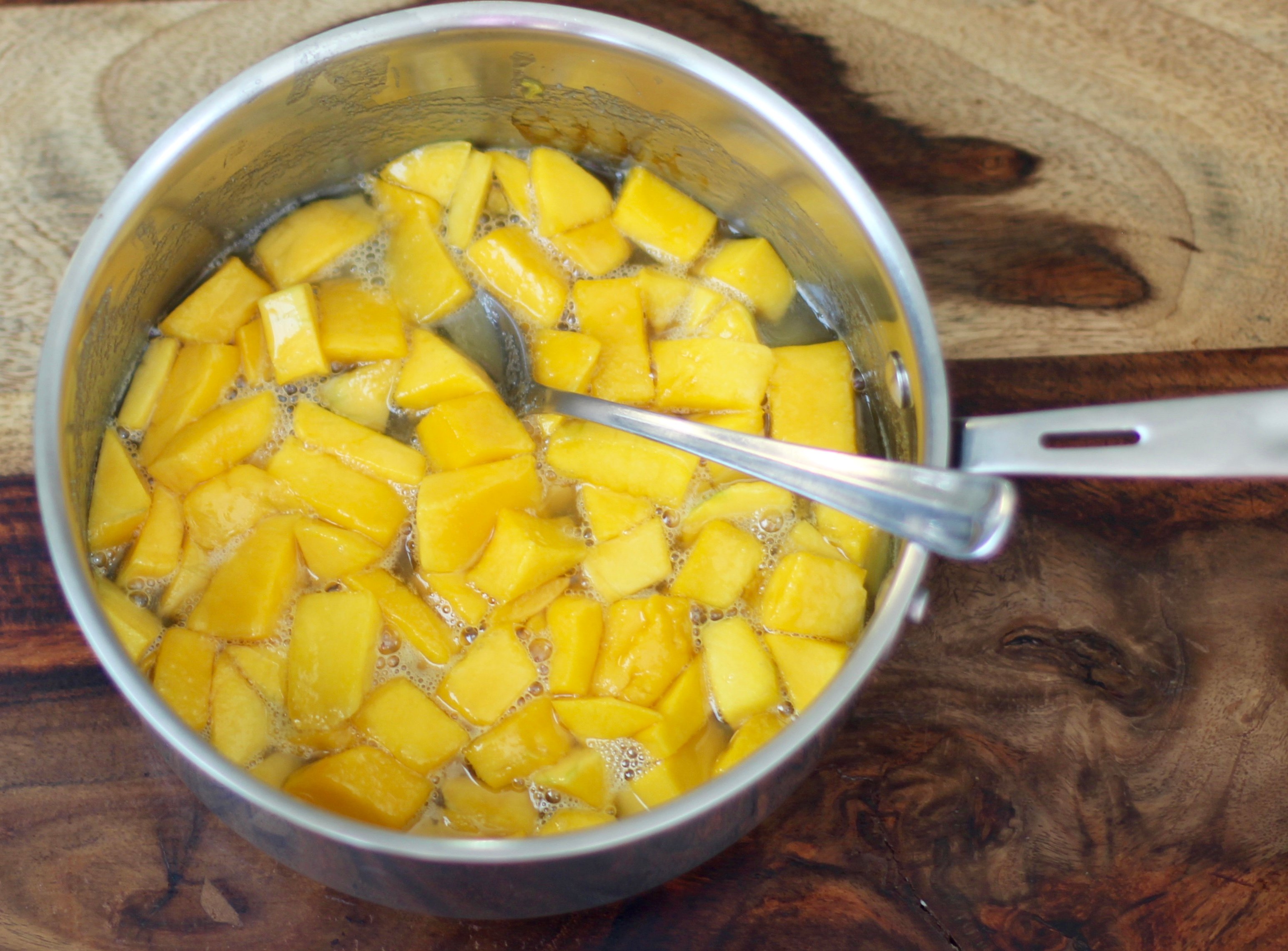 cooked mango in a pot with spoon in it