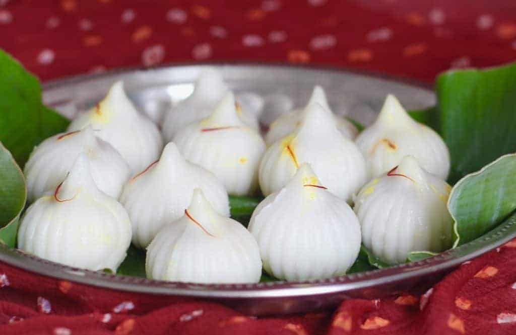saffron garnished modak served in banana leaf