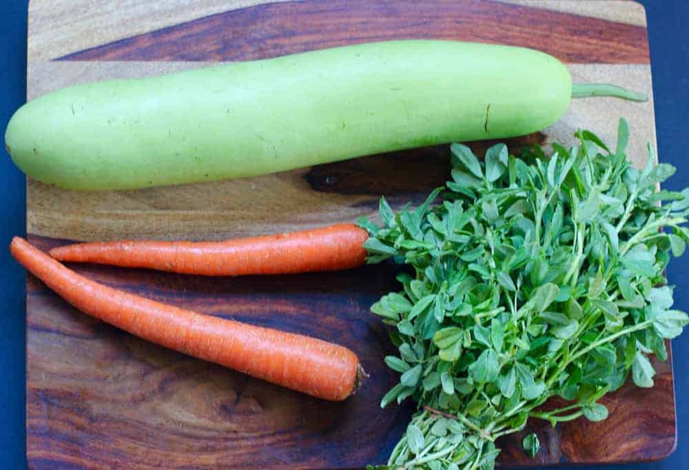 Carrots, dudhi & methi on a cutting board 