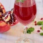 pomegranate juice in a wine glass with mint leaves