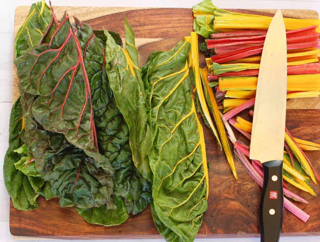 Stems removed from Swiss Chard leaves on a cutting board 