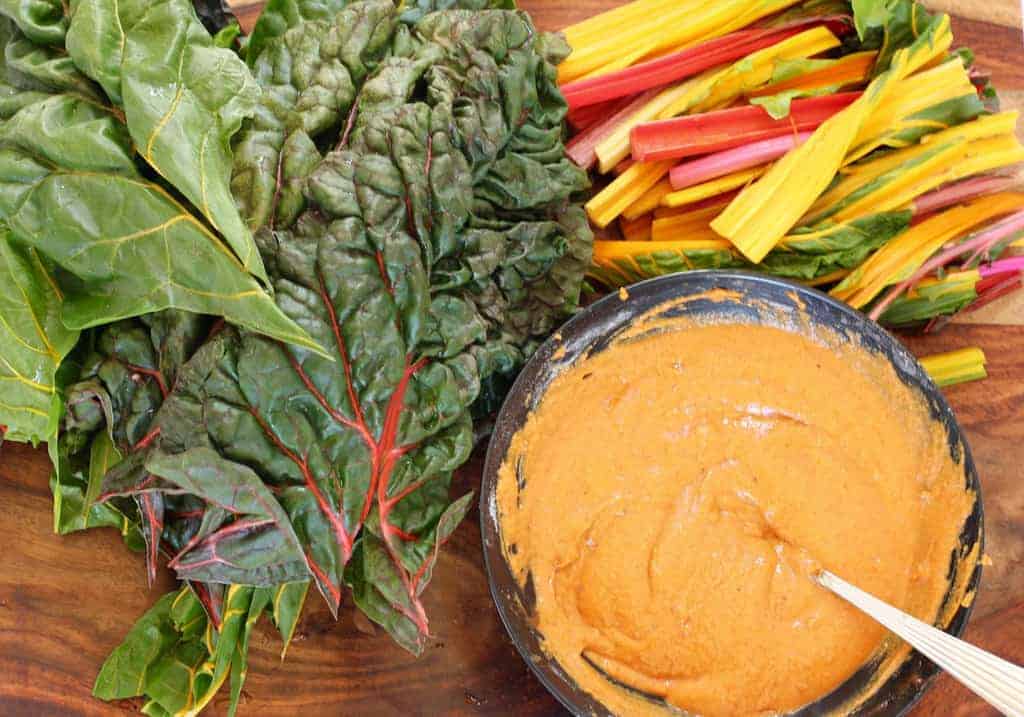 Swiss Chard leaves, stems on a cutting board with gram flour paste in a  bowl