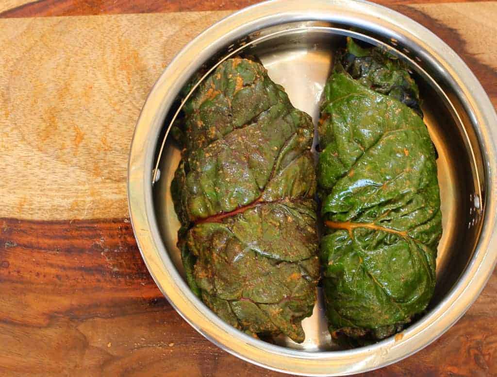 Swiss Chard leaves rolls placed in a steamer basket for Aloo Wadi 