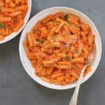 Penne Alla Vodka Pasta served in a white serving bowl with a spoon inside. Another bowl of pasta partially shown in the side.