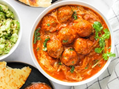malai kofta in a white bowl garnished with cilantro.