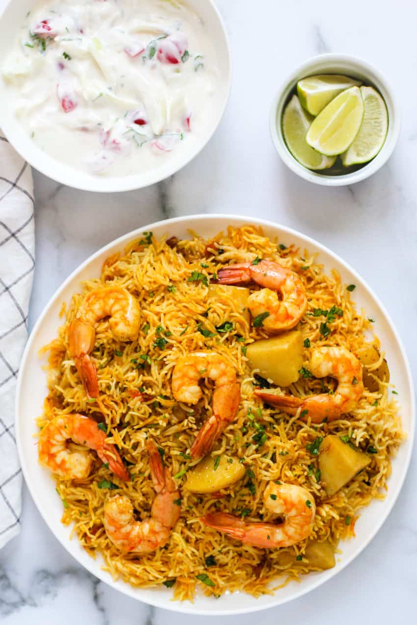 shrimp biryani served with raita and lime wedges 