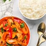 Thai Red Curry Chicken in a white bowl with rice on the side