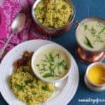 White dinner plate with khichdi and pickle served woth a bowl of kadi. Also a serving bowl of khichdi, kadhi and ghee on the outside