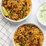 two bowls of chickpea biryani and raita on the side