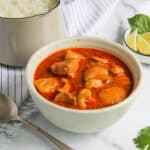 Thai Massaman Chicken Curry in a white bowl with sliced lime on the side