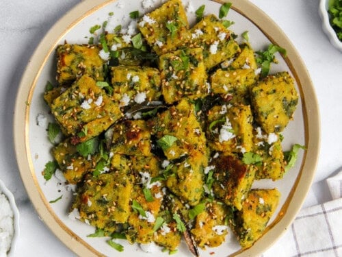 Muthiya garnished with cilantro and freshly grated coconut.