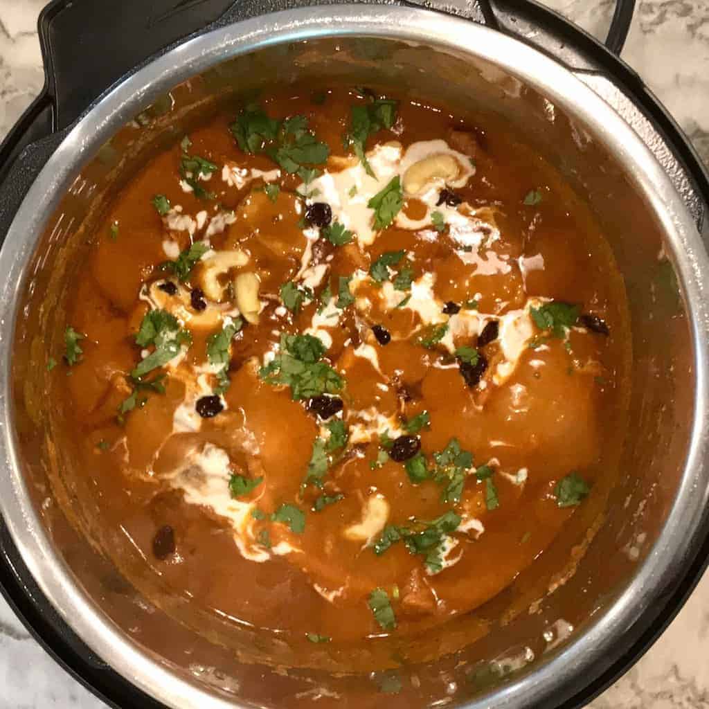 Shahi Chicken Korma in Instant Pot garnished with cream, raisins and cilantro 