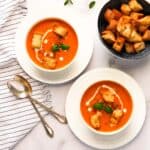 tomato bisque served in two white bowls.