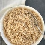 Cooked Brown rice in a white bowl with a fork