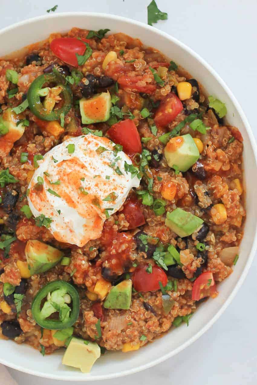 White bowl with chicken enchilada quinoa and a sollop of sour cream 