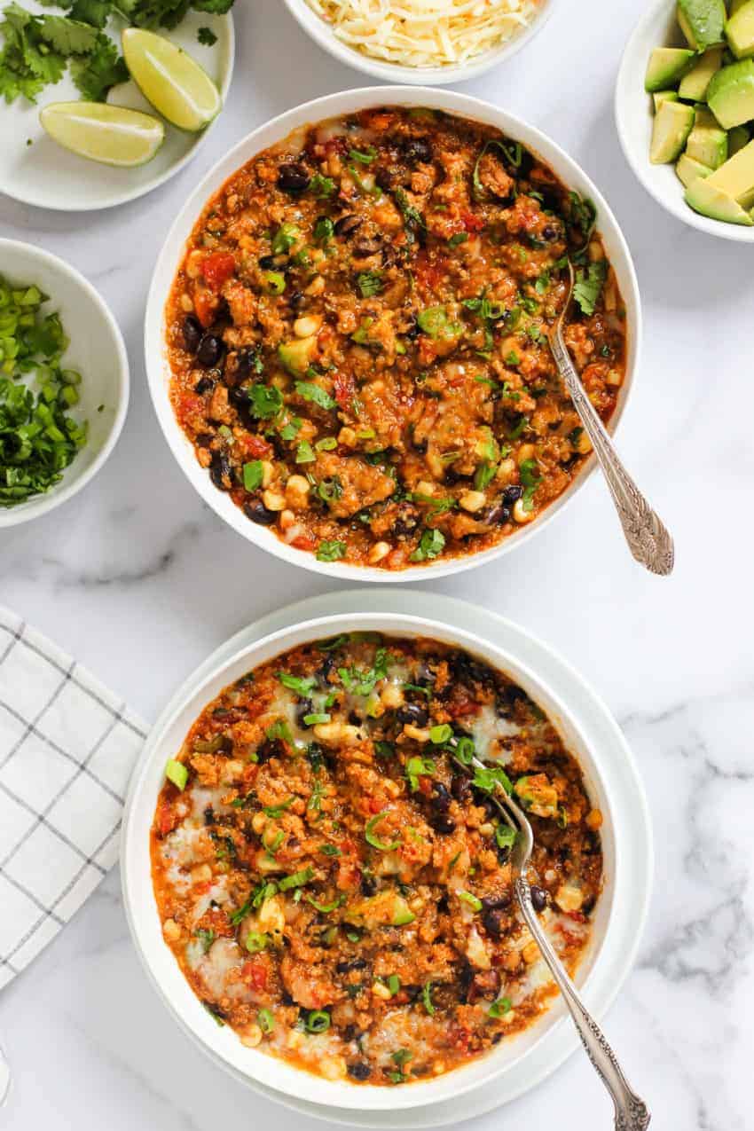 2 bowls of chicken enchilada quinoa garnished with cilantro and scallions