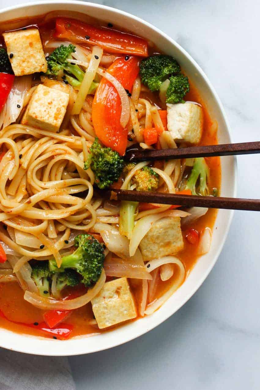 coconut curry noodle soup in a white bowl with chopsticks