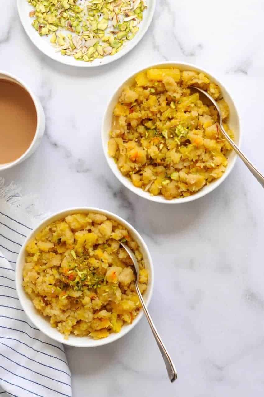 2 bowls of pineapple sheera with a cup of tea and chopped pistachios
