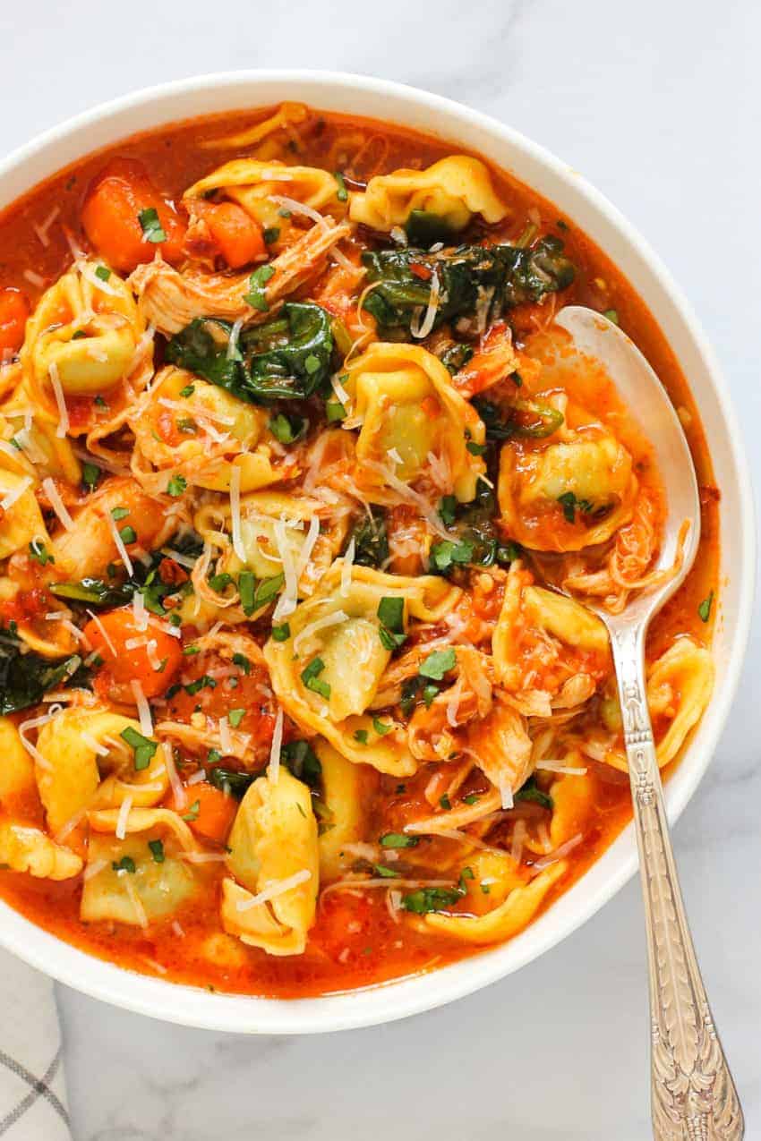Chicken tortellini soup in a white bowl 