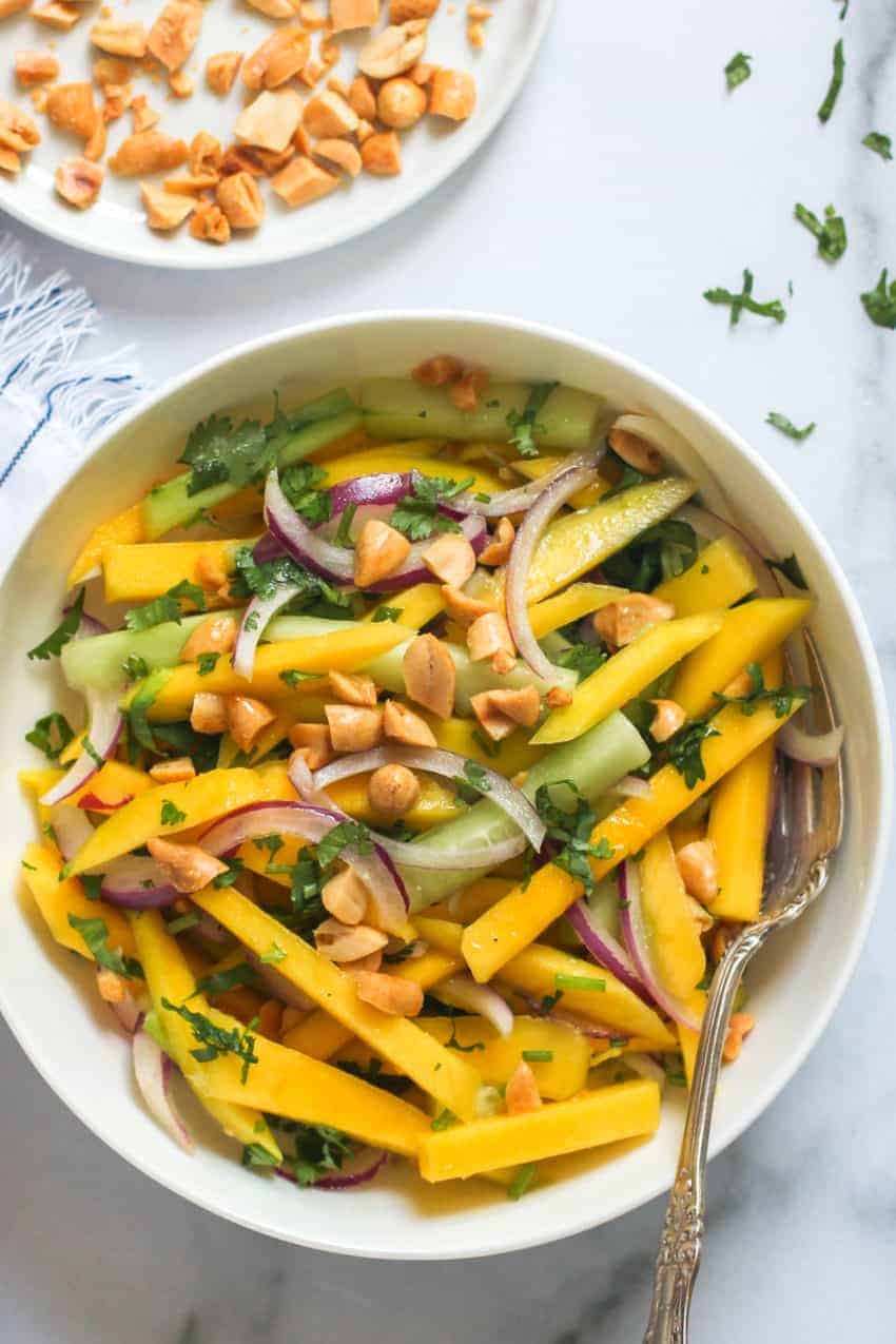 Bowl of mango salad garnished with cilantro and peanuts
