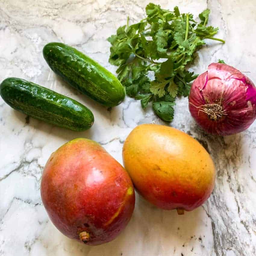 mangoes, cucumbers, red onion and cilantro on countertop
