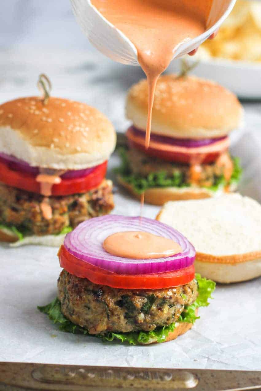 Pouring sriracha mayo over burger
