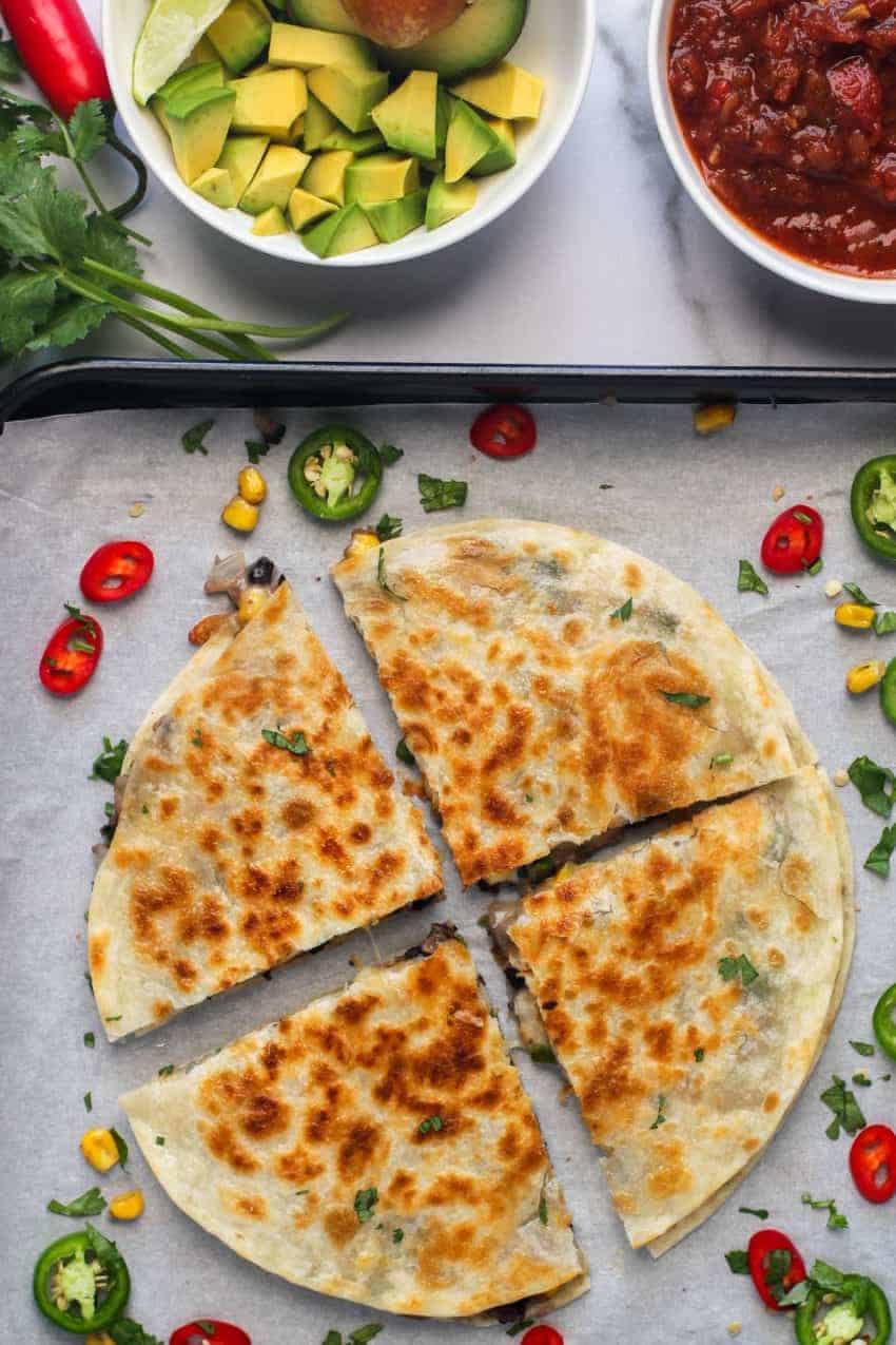 quesadillas on a tray with avocado and salsa on the side