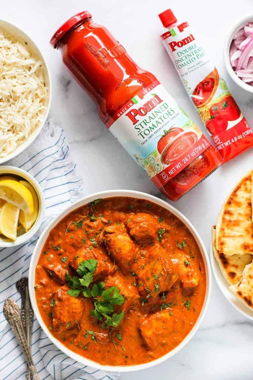 bowl of chicken tikka masala along side a bottle of Pomi strained tomato and a tube of tomato paste 