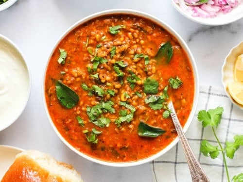 Misal Curry served in a big bowl with all the condiments on the side