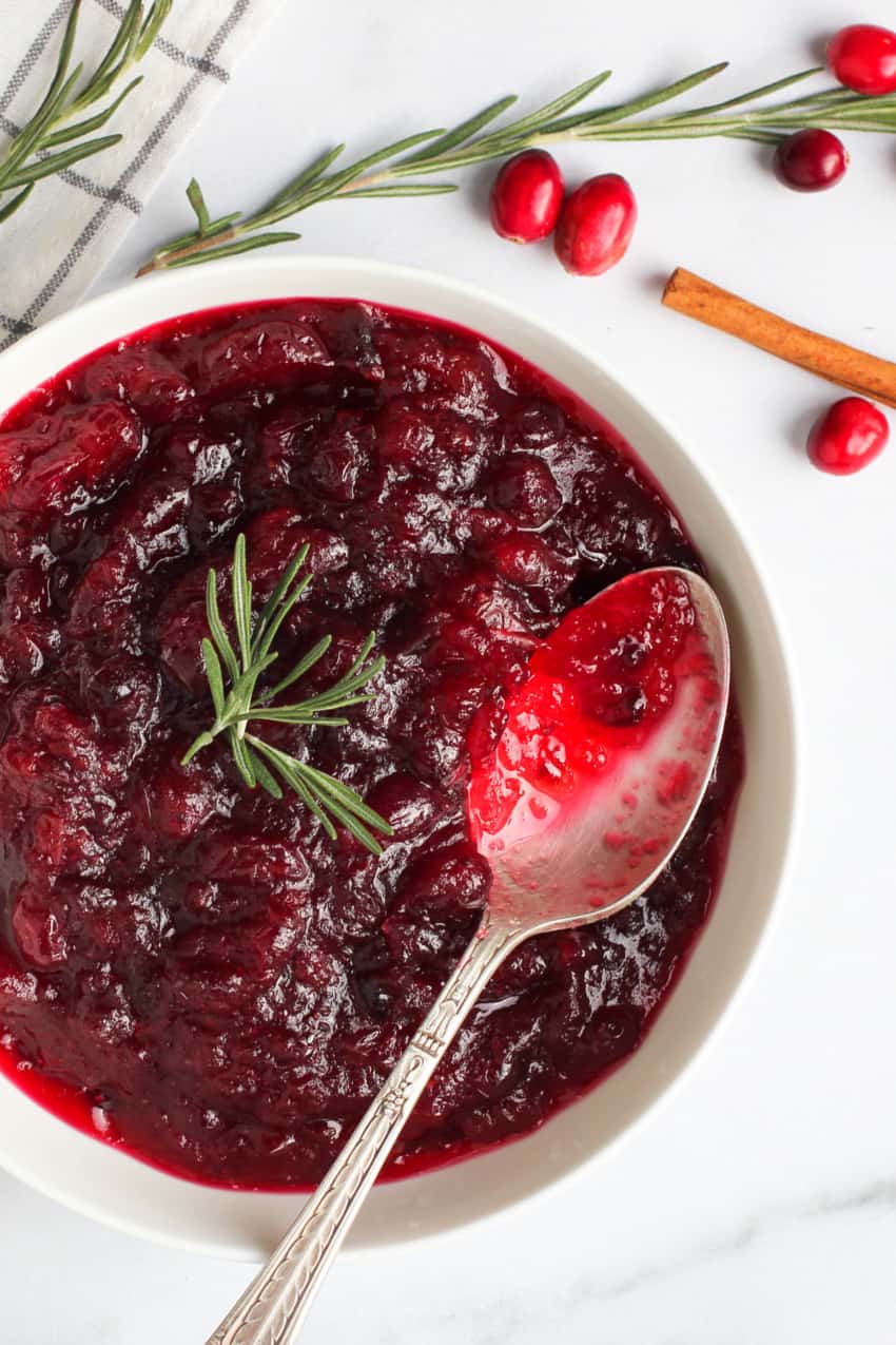 Cranberry sauce in a white bowl garnished with rosemary