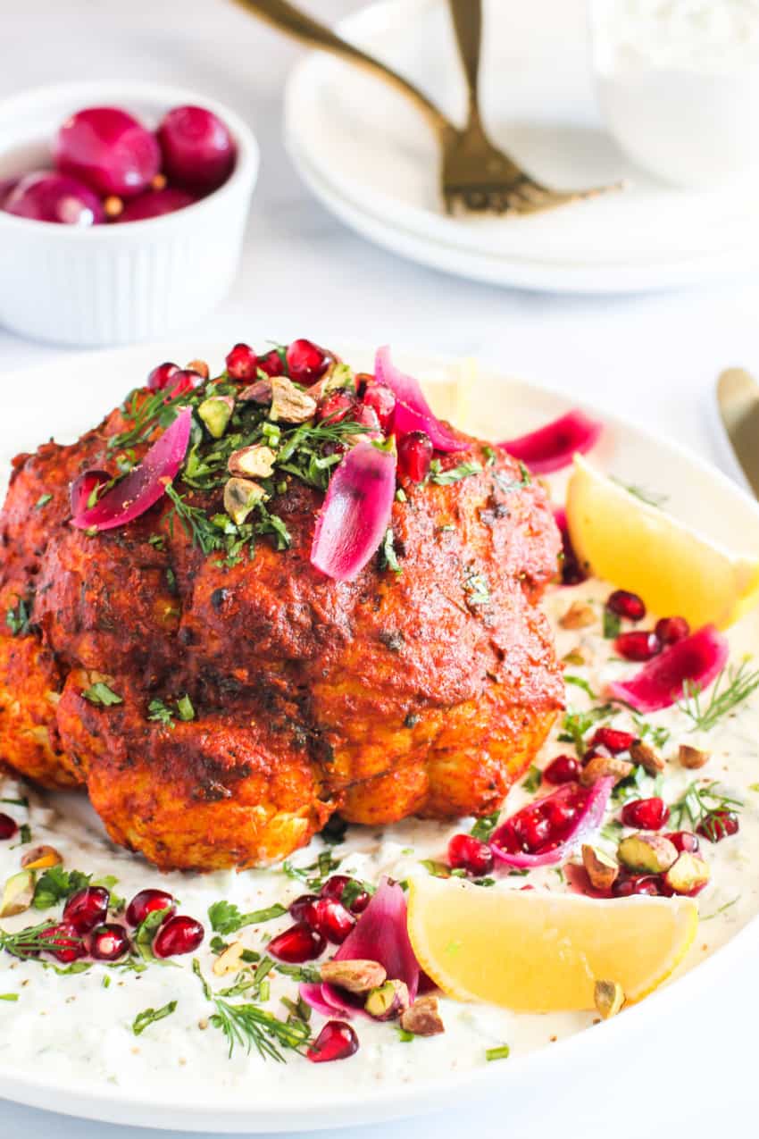 Whole rosted cauliflower garnished with pickled onions, pistachios & pomegranates.