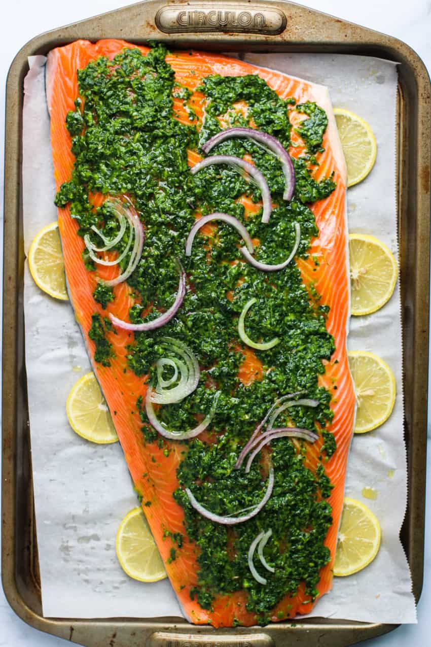salmon coated with marinade and sliced red onion on a baking tray 