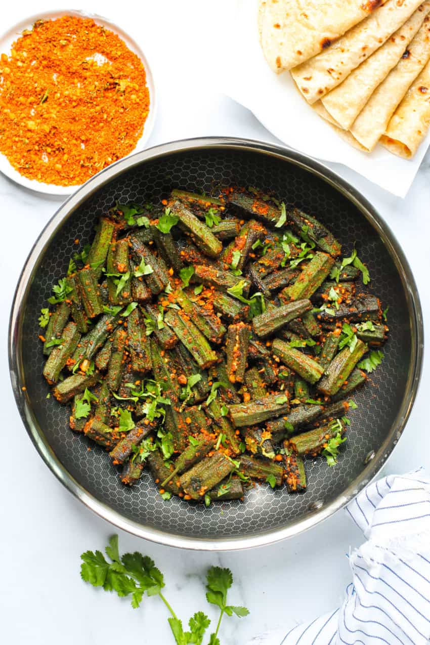 Stuffed okra in a frying pan with roti's on the side 