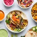 cauliflower tacos in a white bowl with bowls of toppings on the side