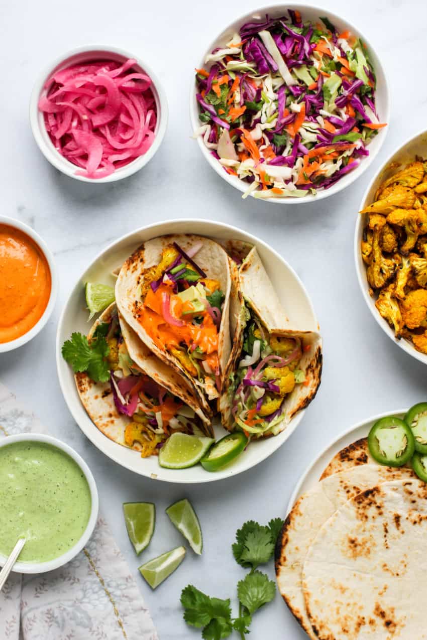 cauliflower tacos served in a white bowl with fixings on the side 