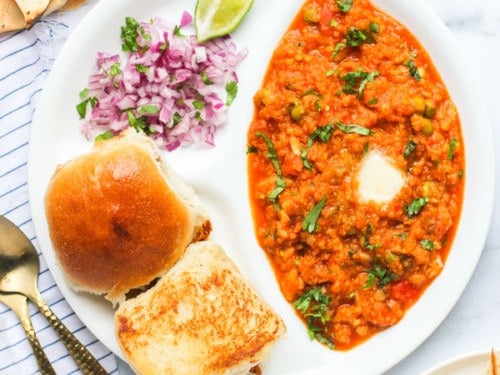 pav bhaji served with diced onions, pickle and papad