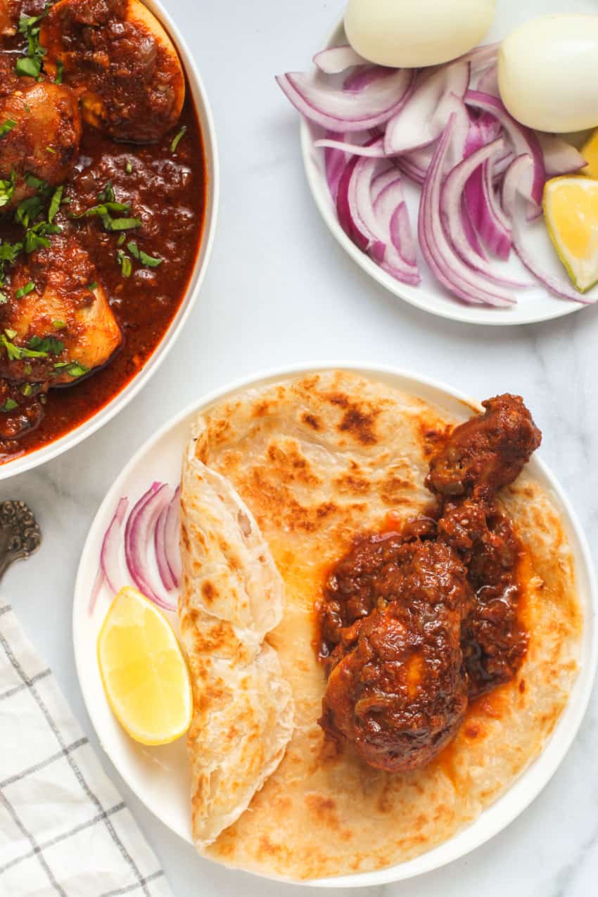 Doro wot served over paratha, with sliced onions and lemons 