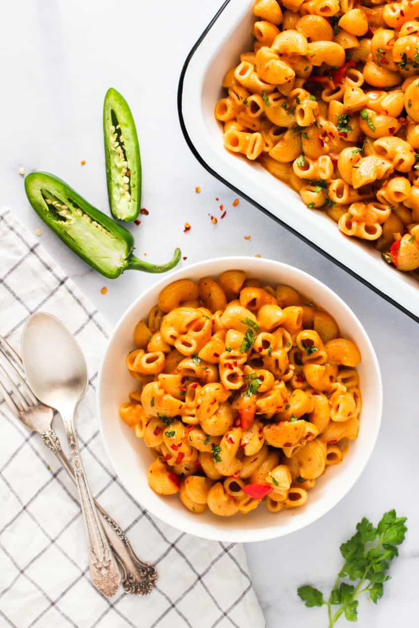 spice mac n cheese in a white bowl next to the serving tray 