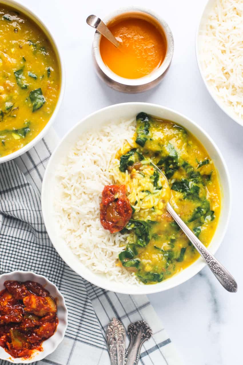 spinach dal and rice served in a white bowl with pickle