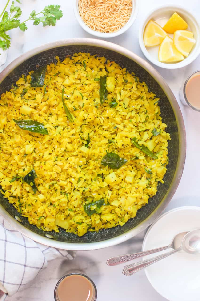 Poha in pan with lemon wedges on the side