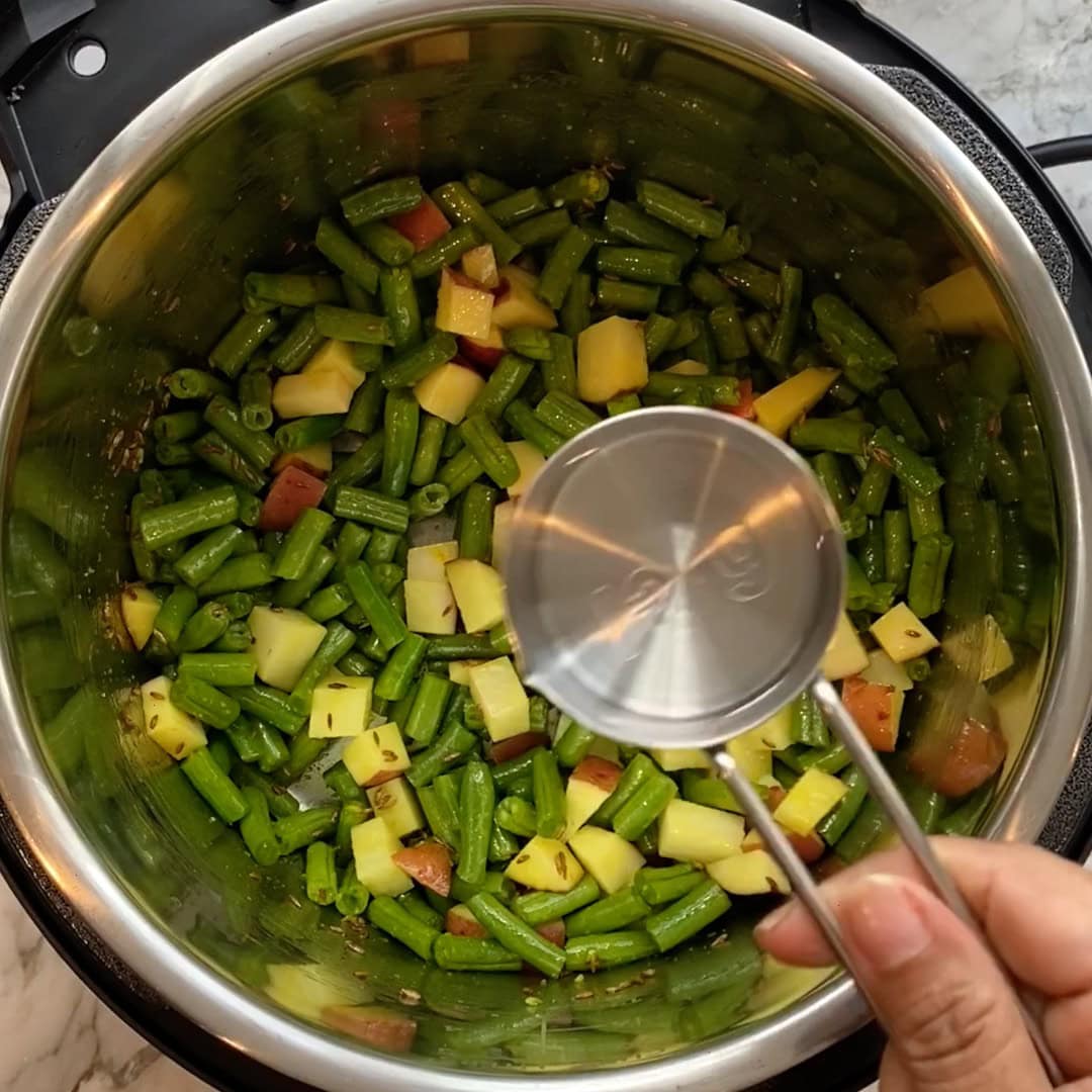 adding water to the green bean curry 