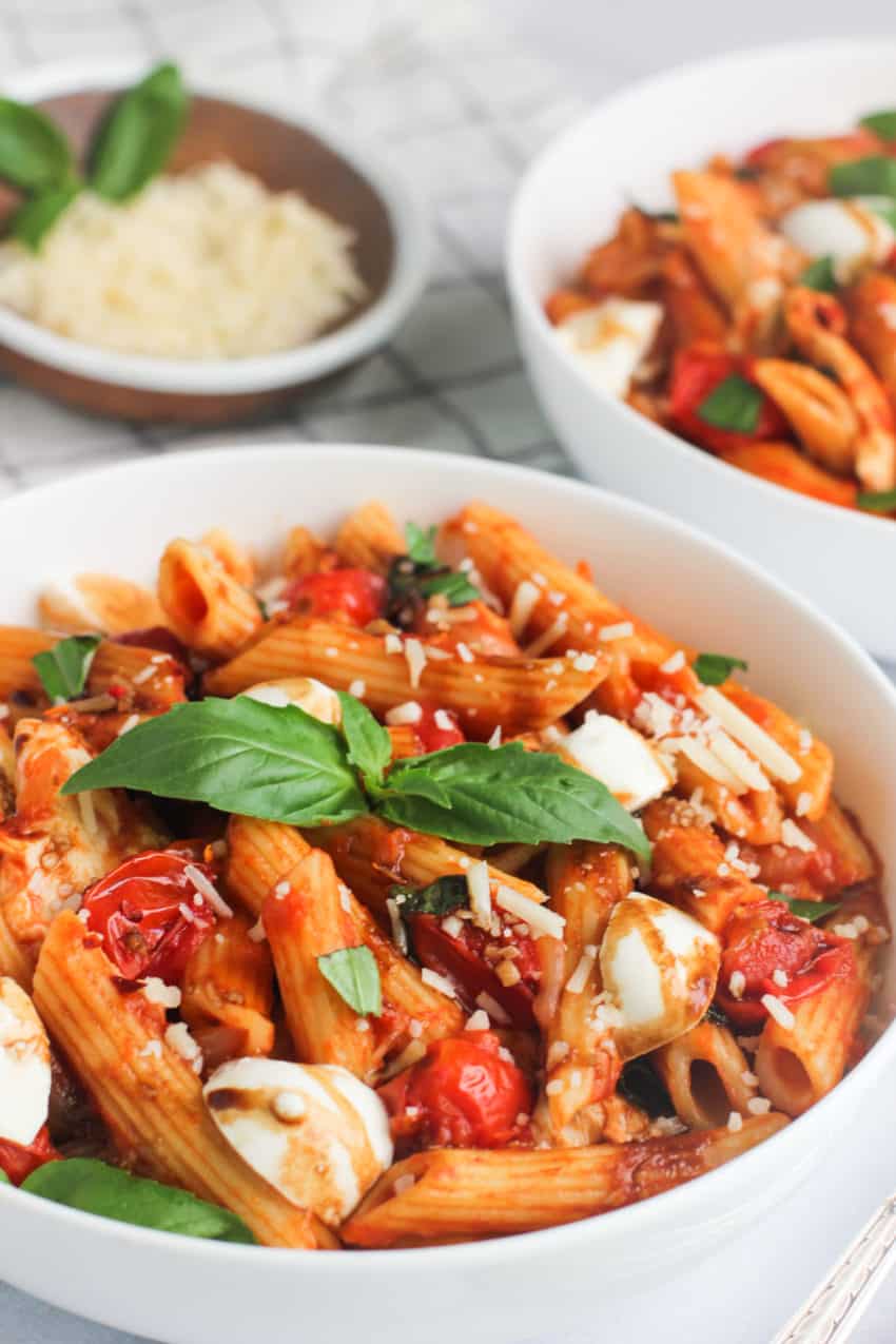 pasta caprese in white bowl with basil on top
