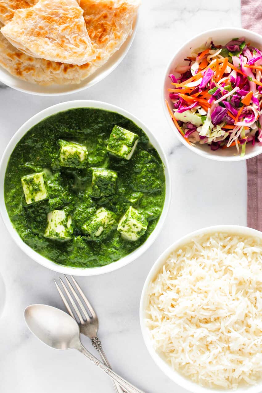 palak paneer served with parathas, rice and cabbage salad